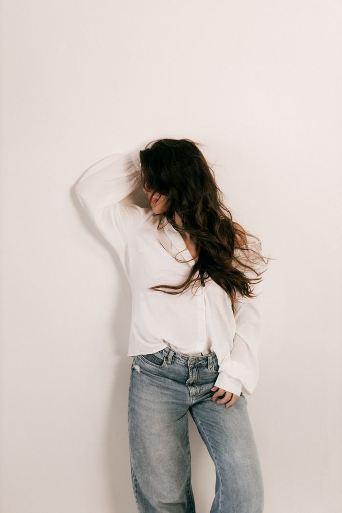 Home Stylish woman posing against a plain background, embracing a relaxed, casual fashion style.
